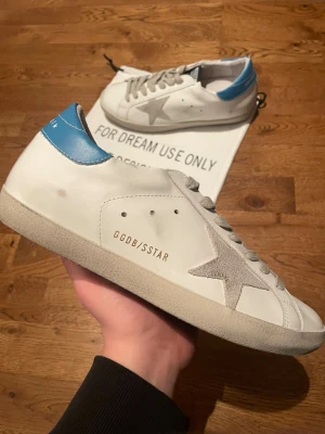 Golden Goose Skor - Snygga sneakers från Golden Goose med den ikoniska beiga stjärnan. Skorna är i bra skick och kommer med dustbag. Modellen heter Superstar och skorna är storlek 42. Pris kan diskuteras 🤝 Skriv ifall ni har fler frågor 💯