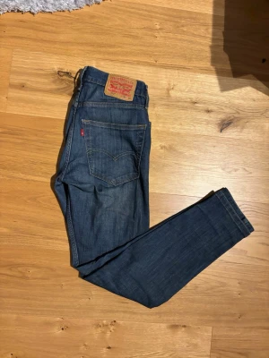 Levi's 512 mörkblå jeans W30 L32 - Säljer ett par Levi's 512 jeans i mörkblå tvätt. Klassisk femficksmodell med smal passform och raka ben. Jeansen har Levi's ikoniska läderpatch bak och röda logotagg på bakfickan. 