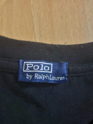 Svart t-shirt från Polo Ralph Lauren - Klassisk svart t-shirt från Polo Ralph Lauren med ikonisk broderad logga i vitt på bröstet. T-shirten har rund hals och korta ärmar. Tillverkad i mjuk bomull för skön känsla och enkel stil.