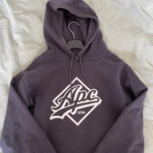 Mörkgrå hoodie från A.P.C. - Säljer en riktigt fet hoodie från A.P.C! Den är i använt skick och trycket har tyvärr börjat spricka lite och färgen har blivit lite solblekt, men den har mycket kvar att ge! Priset kan självklart diskuteras. Storleken är L men skulle snarare säga att den sitter som en stor M då den precis är för stor för mig! 