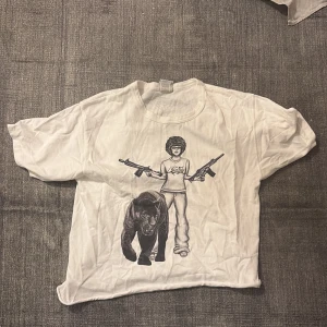 Fet t shirt med tryck  - Vit t-shirt med coolt tryck framtill av en person med afro, två vapen och en panter. På baksidan står det 'ALL POWER TO THE PEOPLE' i stora bokstäver med ett träd och signatur. Skön passform och klassisk rund hals.