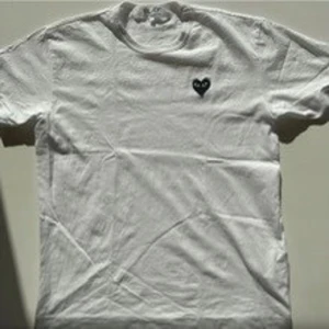 Vit CDG t-shirt - T-shirten är i bra skick använder sällan och passar till allt. Den är vit och har det klassiska broderade hjärt liknade märke i svart.