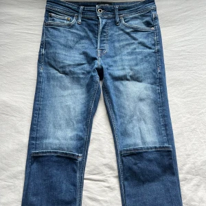 Blå jeans med stora fickor - Snygga blå jeans från Jack & Jones med raka ben. Klassisk femficksmodell med ljus tvätt och kontrastsömmar. Perfekta för dig som gillar en unik twist på dina jeans.