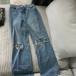 ljusblå slitna jeans - Ljusblå jeans med raka vida ben och slitna hål på båda knäna. normal passform och hög midja. Xs men skulle även passa S