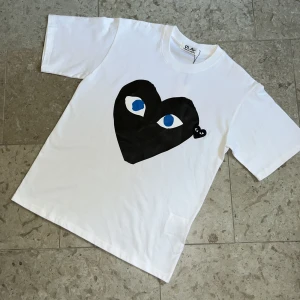 Vit Cdg Play t-shirt - Säljer en vit t-shirt från Cdg Play med stort tryck med logga på framsidan i storlek S, T-shirten är i nyskick och fraktas inom 24h✅