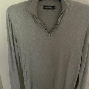 Grå grisch tröja - Snygg grå grisch tröja från Dressmann i mjuk Supima-bomull. Tröjan har en hög krage med half zip-dragkedja och är 100% bomull