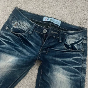 Blå jeans med slitningar och tvättad look - Snygga blå jeans med cool tvättad effekt och slitningar framtill och baktill. Klassisk femficksmodell med raka ben och normal passform. Jeansen har tydliga kontraster och detaljerade sömmar som ger en trendig streetkänsla. Har ej bilder på då dom va för små för mig  midjemått 34cm, innerbenslängd 74cm, gren 16.5cm hör av er vid frågor 