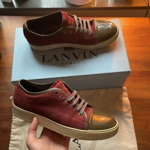 Vinröda Lanvins Uk8 - Snygga sneakers från Lanvin i vinröd mocka med grå snörning och glansig mörkgrå lacktå. Skorna har en beige sula och klassisk låg profil. Perfekta för dig som vill ha en unik och lyxig touch på din outfit. Box och dustbag medföljer, uk8