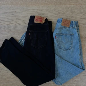 Levi's 501 jeans svart & ljusblå - Två par klassiska Levi's 501 jeans, ett par i svart denim och ett par i ljusblå tvätt. Båda har raka ben, femficksdesign och ikonisk läderpatch bak. Perfekta för dig som gillar tidlös stil och vill ha jeans med snygg passform och autentisk känsla.
