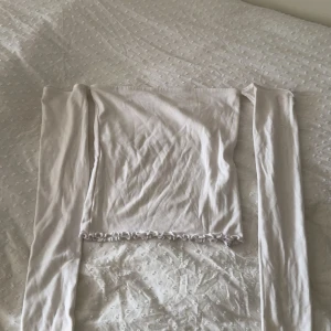 Vit offshoulder topp från Gina Tricot - Säljer en vit offshoulder topp från Gina Tricot i storlek XS. Toppen är croppad med långa ärmar och har en söt volangkant nertill och vid ärmsluten. Gjord i mjuk bomull som sitter tight och framhäver axlarna på ett snyggt sätt.