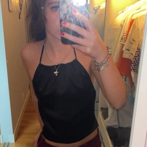 Svart halterneck linnetopp från NA-KD - Säljer en svart halterneck linnetopp från NA-KD i glansigt material. Toppen har tunna knytband i nacken och ryggen. Storlek 32