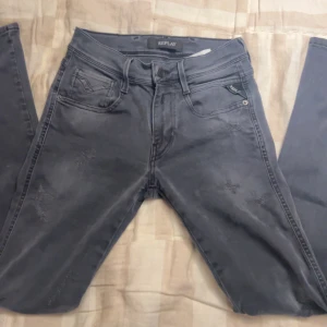 Replay grå jeans med slitningar - Säljer ett par grå jeans från Replay med snygga slitningar och klassiska fem fickor. Jeansen är slim fit och perfekt till hösten 