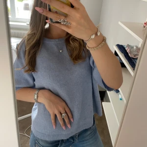 Ljusblå stickad tröja från 157 - Superfin ljusblå stickad tröja från 157 med kortare ärmar och avslappnad passform. Perfekt till jeans för en chill look. Mjuk och skön, enkel att styla med smycken eller accessoarer.
