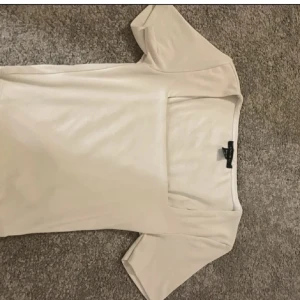 vit topp med fyrkantig ringning Amisu - Säljer en stilren vit topp från Amisu i storlek S. Toppen har korta ärmar och en snygg fyrkantig ringning som ger en modern vibe. Materialet är mjukt och stretchigt, perfekt för att matcha med jeans eller kjol. Enkel och clean design utan mönster eller detaljer.