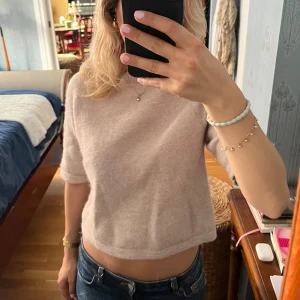 Beige stickad tröja från & Other Stories - Supermjuk beige stickad tröja från & Other Stories. Tröjan har rund halsringning, halvlånga ärmar och en enkel, stilren design. Perfekt för lager-på-lager och passar snyggt till jeans eller kjol.