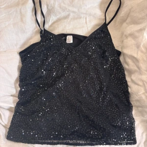 Svart glittrigt linne  - Säljer en svart glittrig topp från H&M