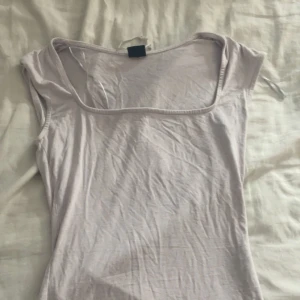 Vit topp med fyrkantig ringning Gina Tricot - Säljer en ljusrosa topp från Gina Tricot i storlek XS. Toppen har en snygg fyrkantig ringning och är ärmlös med en tight passform. Perfekt att styla med kjol eller jeans för en clean look.