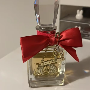 Viva La Juicy parfymflaska - Juicy Couture Viva La Juicy i snygg flaska med röd rosett och guldiga detaljer. Perfekt för dig som vill sticka ut och addera lite glamour till din vardag. Säljs med originalförpackning. Endast parfymen och förpackningen ! 50ml men använd några gånger som syns på bild. Nypris 850. Paketeras bra och säkert 