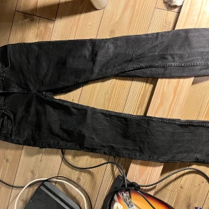 Svarta slim jeans  - Svarta jeans med klassisk femficksdesign och raka ben. Jeansen har en enkel look utan synliga detaljer och är tillverkade i ett robust denimtyg. Perfekta för dig som gillar en stilren och tidlös vibe.