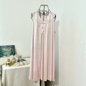 Ljusrosa nylonklänning från Vanity Fair - Supersöt ljusrosa nylonklänning från Vanity Fair med spetsdetaljer vid halsringningen och en liten rosett framtill. Materialet är tunt och är något genomskinligt. Har en fläck på baksidan (se sista bild). Passar bäst storlek L-XL (40-44), dockan är i storlek 34.