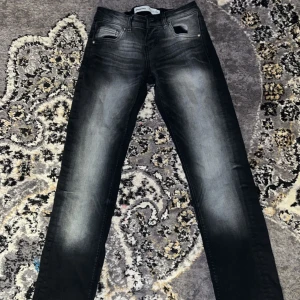 Svarta lågmidjade jeans  - Snygga svarta jeans med skinny passform och coola blekta detaljer längs benen. Jeansen har klassisk femficksdesign och är tillverkade i stretchigt denim för skön komfort. Perfekta för dig som gillar en modern och smal siluett.