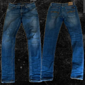 Blå jeans från Nudie Jeans W29 L32 - Snygga blå jeans från Nudie Jeans med klassisk femficksdesign och orangea sömmar på bakfickorna. Modellen har rak passform och normal midja, tillverkade i slitstarkt denim. Perfekta för dig som gillar stilrena och tidlösa jeans.