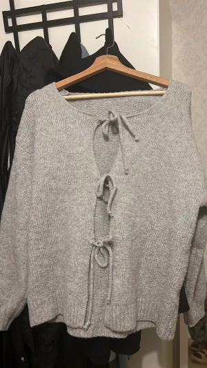 Grå stickad tröja med snörning - Den är storlek M men är väldigt lös så skulle säga typ L. Säljer en grå stickad tröja med snygg snörning framtill. Tröjan har långärmade ärmar och en loose passform som gör den extra chill. Perfekt för dig som gillar detaljer och vill ha något mysigt och stilrent i garderoben.