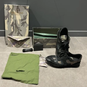 Valentino Garavani Rockrunner sneakers - Snygga Valentino Garavani Rockrunner sneakers i svart med camouflage-mönster i grått, beige och grönt. Skorna har snörning, rund tå och platt sula. Tillverkade i en mix av skinn och mocka för en lyxig känsla. Kommer med originalkartong, dustbag och extra skosnören. Några skavanker på sko och låda därav priset