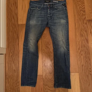 Replay waitom blå jeans med slitningar - Blå Replay waitom jeans med snygga slitningar och lite trasig vid knät. Klassisk femficksmodell med coola bakfickor och läderpatch i midjan. Jeansen har en rak passform och är tillverkade i mjukt denimtyg för skön känsla.