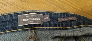 Blå jeans från Dressmann Regular Fit - Snygga blå jeans från Dressmann i modellen Regular Fit. Klassisk femficksdesign med raka ben och normal passform. Jeansen har en mörk tvätt med lätt slitning och är tillverkade i slitstarkt denimtyg. Perfekt för dig som gillar enkel och stilren look. Originalpris: 800