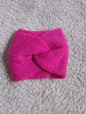 Rosa stickat pannband med twist - Snyggt rosa stickat pannband med twistad front som jag gjort själv . Perfekt för att hålla sig varm i vinter och samtidigt addera färg till din outfit. Mjukt och bekvämt material som sitter skönt runt huvudet.