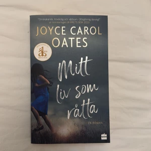 Mitt liv som råtta - En gripande roman av Joyce Carol Oates, nominerad till Årets Bok 2020. Omslaget visar en ung tjej i blå klänning som springer genom ett fält, vilket ger en känsla av dramatik och spänning. Perfekt för dig som gillar starka berättelser och oförglömliga läsupplevelser.