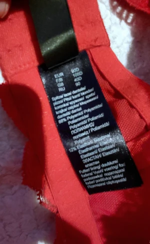 Röd Bh från Bodyflirt, 90D - Säljer en snygg röd Bh från Bodyflirt med blommig spets och dubbla axelband. Bh har vadderade kupor. Oanvända 