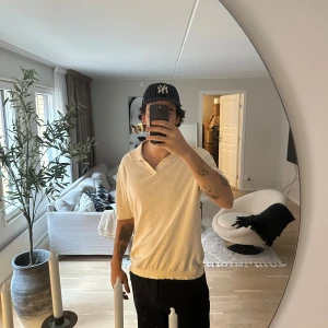 Beige pikétröja från ARKET i bomull - Säljer en stilren beige pikétröja från ARKET i storlek L. Tröjan har klassisk krage, v-ringad hals och korta ärmar. Tillverkad i mjuk bomull som känns skön mot huden. Perfekt för dig som gillar en clean och avslappnad look.