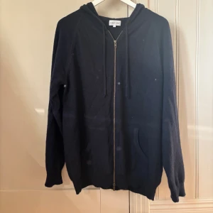 Mörkblå hoodie i kashmir från Davida - Mysig mörkblå hoodie från Davida i mjuk kashmir. Tröjan har huva med snörning, hel dragkedja framtill och två fickor. Perfekt för dig som vill ha en chill och lyxig look. Långärmad och loose passform. Pris kan diskuteras vid snabb affär.👍