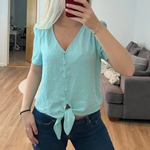 Turkos topp - Turkos topp aldrig använd. Puffiga ärmar, knappar fram och knyte fram 