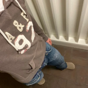 Abercrombie & Fitch Hoodie - Säljer en brun hoodie från Abercrombie & Fitch i storlek L. Tröjan har broderad A&F 92 på bröstet, snörning vid huvan och en klassisk känguruficka framtill. Mjuk insida och långa ärmar, perfekt för chill dagar. Om du undrar något är det var att fråga🙌✅