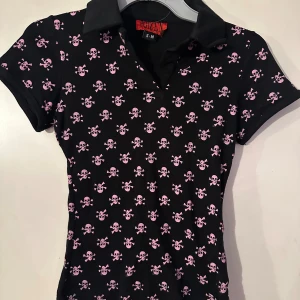 Topp med krage fr Poizen storlek S/M - Snygg topp med rosa dödkallar. Från Poizen. Storlek S/M. 