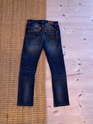 Blå  jeans från Nudie Jeans - Nudie jeans i w29 asfeta jeans som har en skön fade och några astetiska hål. Kom dm vid funderingar💛