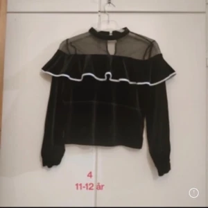 Svart sammetstopp med volang och mesh - Säljer en fin volang tröja. Svart sammetstopp med volang och mesh i strl 152 alltså XXS 