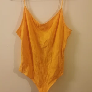 Gul/orange linne stringbody från H&M - Gul/orange stringbody från H&M med tunna axelband och ribbad struktur. Tillverkad i 86% LivaEco viskos som känns mjuk mot huden. Oanvänd 