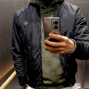 Svart bomberjacka från J.Lindeberg - Snygg svart bomberjacka från J.Lindeberg med röd insida och ribbade muddar. Jackan har dragkedja framtill, två fickor med knapp och en cool patch på bröstet. Perfekt för dig som vill ha en stilren och modern look.rintigt snygg jacka passar hela året om jacka yes ( tkr om att ta kort i hissen för att visa så bra så möjligt o ärlighet så klart använt kanske 20 ggr ser väldigt fräsch på också pris 800