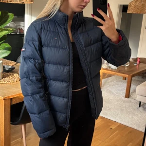 Dunjacka - Marinblå dunjacka från Tommy Hilfiger. Har ett lagat hål på ena armen (syns på sista bilden), därav det låga priset. Dock tänker man inte på det om man inte vet om det. Har ingen luva. (Tips, säljs billigare på min Vinted då de inte tar 20% av försäljningen, @emmasandbrg). 