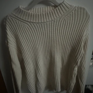 Ribbad beige stickad tröja - Säljer en beige stickad tröja med ribbad struktur och rund hals. Tröjan har långärmade ärmar och är perfekt för dig som gillar en enkel men snygg look. Passar dig som vill ha en mysig och stilren tröja till garderoben.
