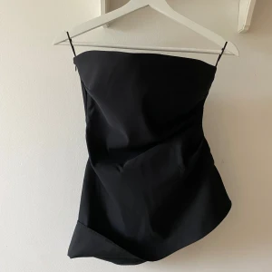 Svart Zara tubtopp med asymmetrisk kant - Säljer en svart tubtopp med snygg asymmetrisk nederkant. Stl L men är mer som stl S 