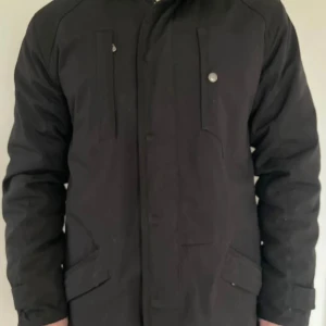 Svart parkajacka Peak Performance L - Svart parkajacka från Peak Performance i storlek L. Jackan har huva, flera fickor med lock och knappar samt dragkedja framtill. Materialet är slitstark polyester med quiltad insida för extra värme. Perfekt för kalla dagar och har en clean, stilren look. Avtagbar lättviktsjacka, för att gå från varm till vår och höstjacka. (Nypris 5000kr). Sparsamt använd! 