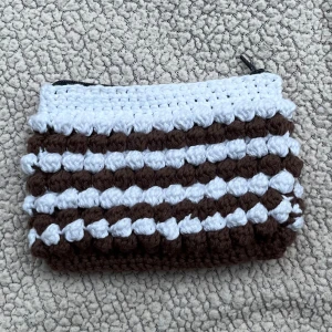 Virkad bubbel necessär - Egenvirkad bubbel necessär i mörkbrun, vitt garn 🧶🤎🤍perfekt att ha nycklar, plånbok, laddare, läppstift, små prylar mm.  Går även att få i andra färger 🤎