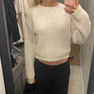 Vit stickad tröja - Säljer en vit stickad tröja med grov struktur och fin passform. Tröjan har rund hals och långa ärmar med ribbade muddar. Perfekt för dig som gillar en enkel men snygg look.