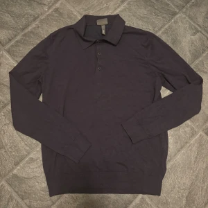 Mörkblå pikétröja från H&M - Snygg mörkblå långärmad pikétröja från H&M i slim fit-modell. Tröjan har klassisk krage och knäppning med tre knappar framtill. Perfekt för dig som gillar en stilren och enkel look. Tillverkad i mjuk bomull för skön känsla hela dagen.