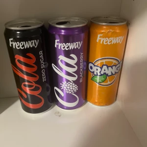 De 3 eftertraktade lidl burkarna. Freeway soda. - Bilden visar tre burkar läskedryck av märket Freeway i smakerna Cola Zero Sugar, Cola Blackberry och Orange. Burkarna är öppnade och placerade på en hylla. Ingen elektronikprodukt syns på bilden.